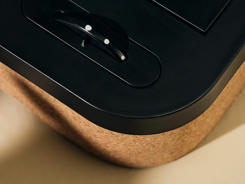 Close-up of a modern device with a black matte finish and a cork textured base, featuring a small black lever with white dots.