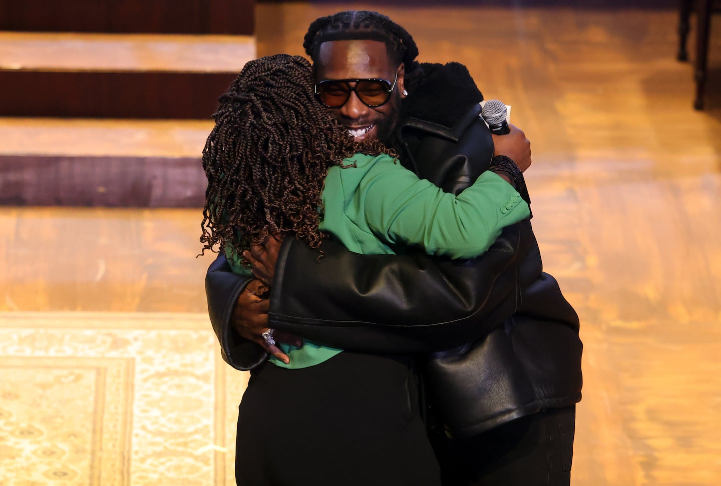 Nigerian musician Burna Boy (right) embraces Boston City Council President Ruthzee Louijeune as he arrives to speak to students.