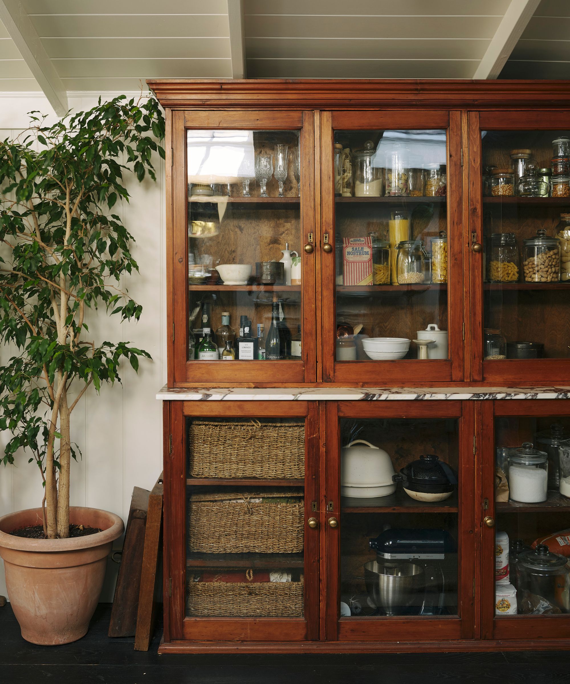 A kitchen with warm white walls and an antique cupboard used as a pantry