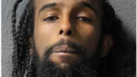 Met Police A police mugshot of Elyas Moussa, who has long dark dreadlocks and a beard