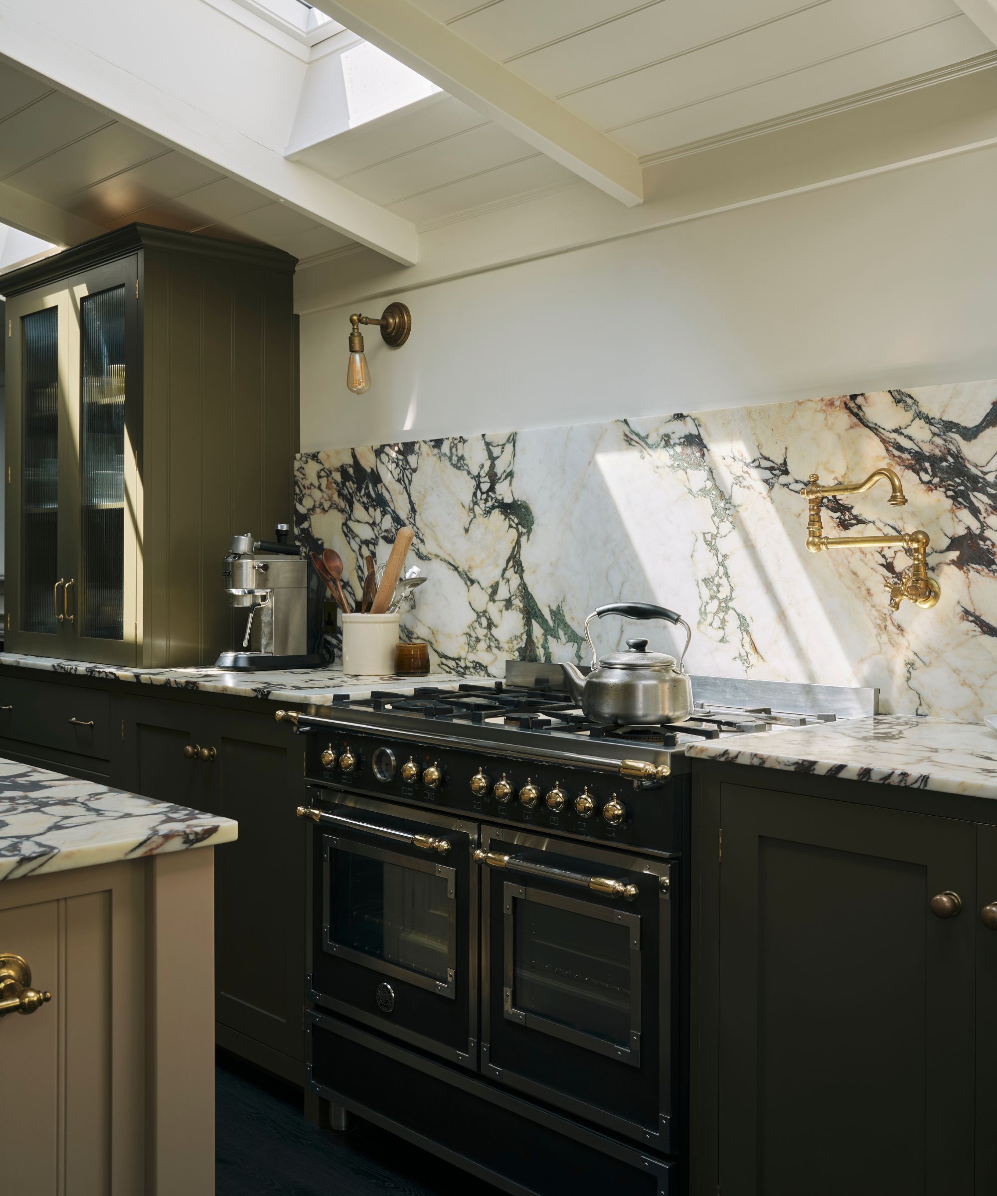 An olive green kitchen with marble countertops and a countersplash