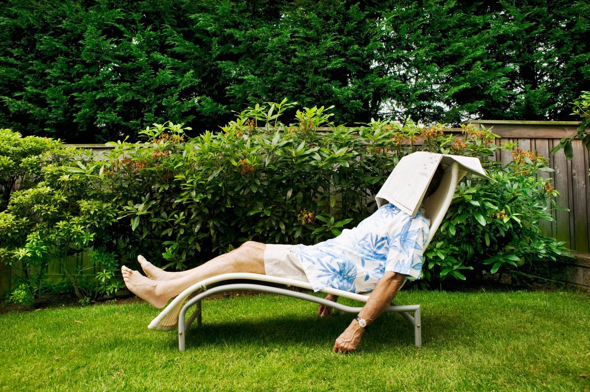 Man napping in his backyard with newspaper over his head