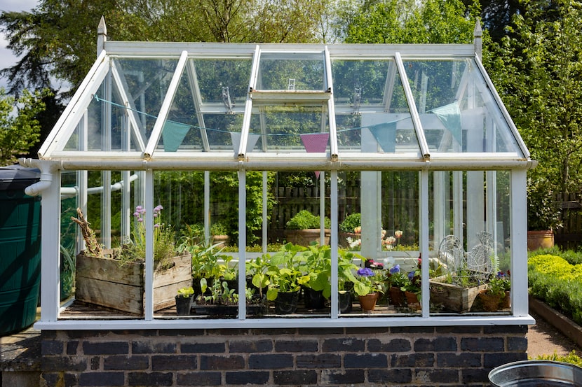 A garden plot with seedbeds and a glass greenhouse in the centre of kitchen garden. A...