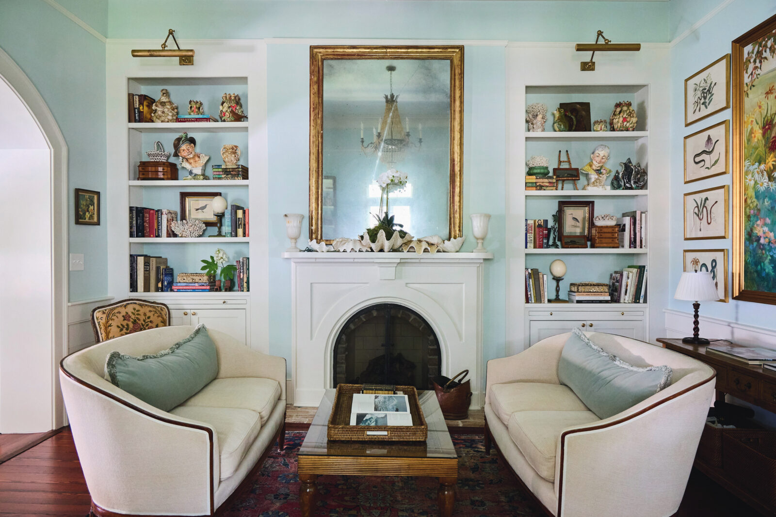 A living room with a white fireplace and mirror