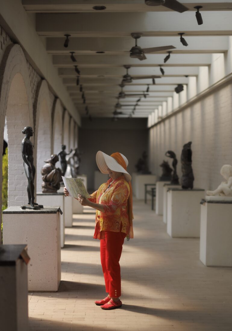 A woman stands in a sculpture courtyard