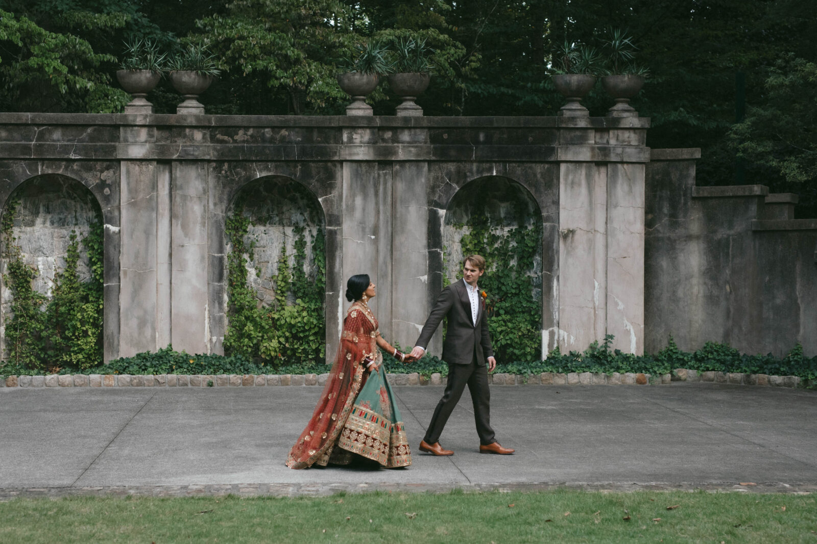 A couple walks in front of a garden wall