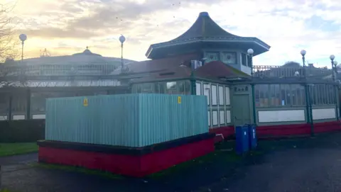 An up-to-date shot of the Winter Gardens on quite a grey day with a peaked roof and a dome visible behind it.