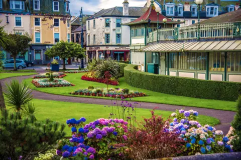 Getty Images A colourful old image of the Winter Gardens in good condition, with well-tended gardens around it, and the road behind lined in shops with bunting hung on the buildings.