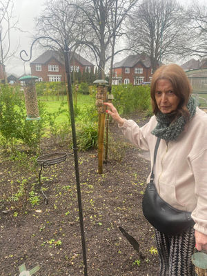 Resident from HC-One’s Lime Trees Care Home placing bird feeder in the garden