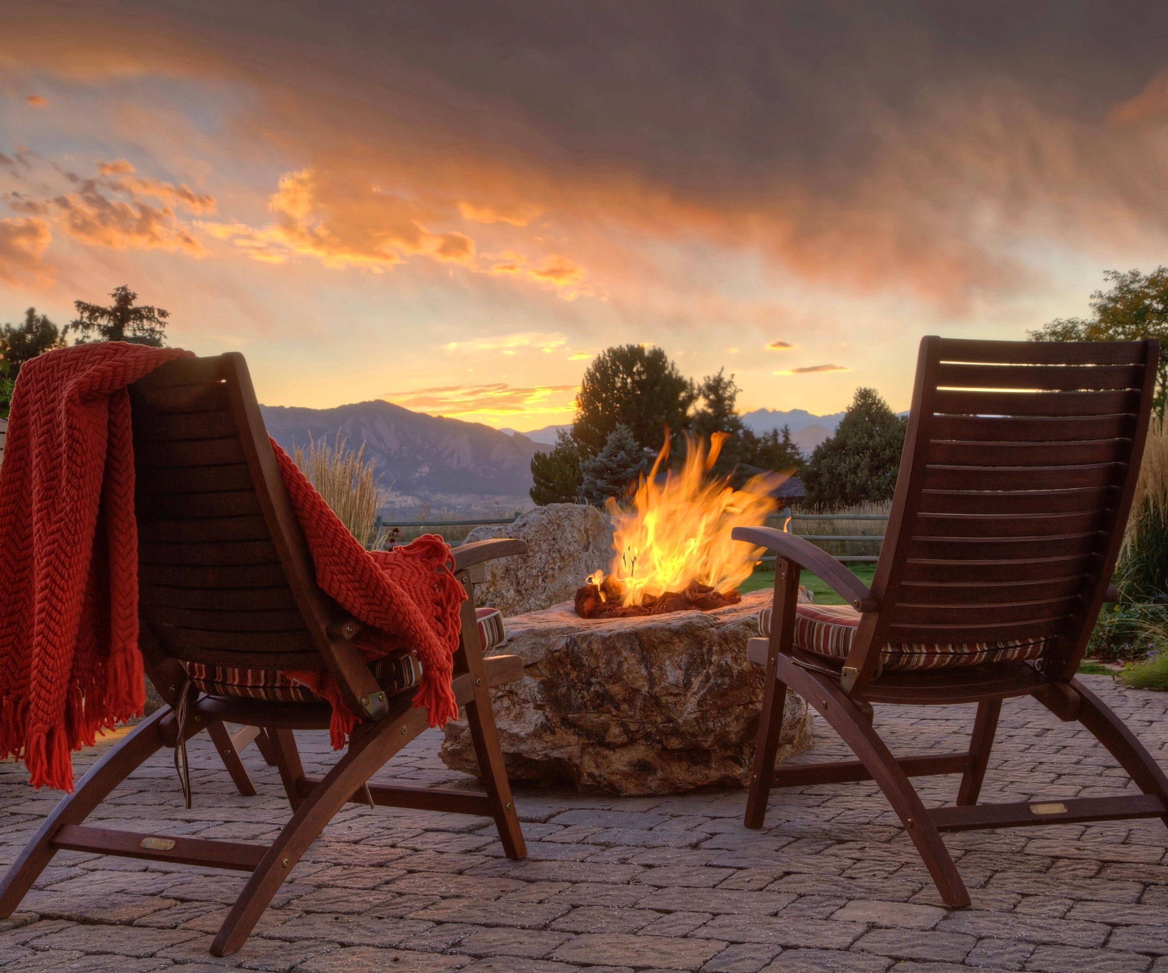 fire pit with two garden chairs and red throw, with view to mountains on the horizon