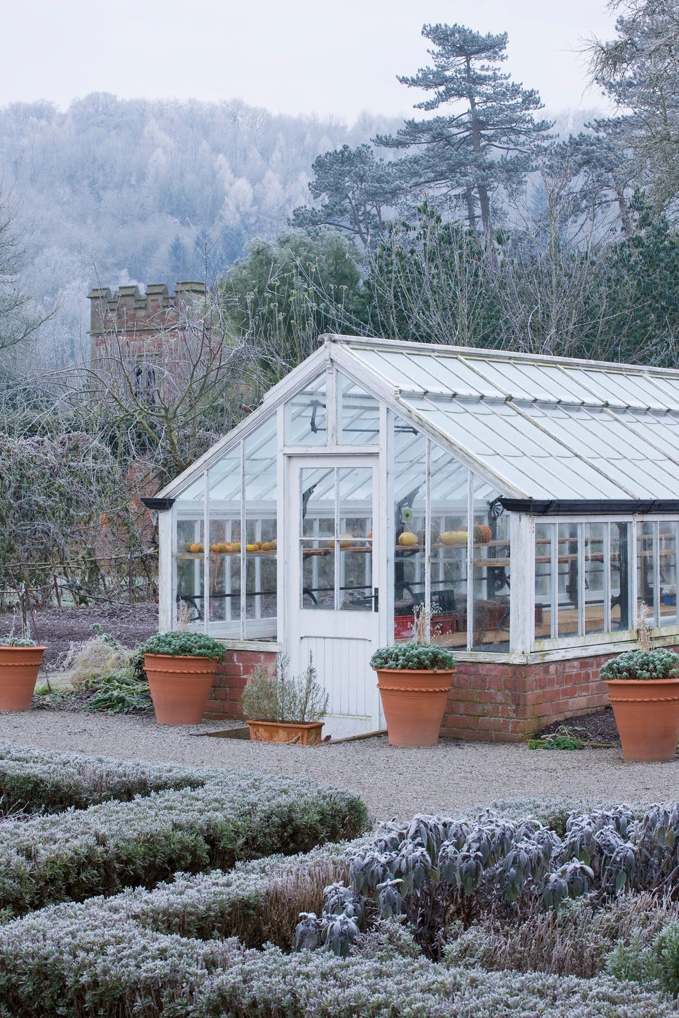 hampton court castle and gardens, herefordshire: the organic kitchen/ vegetable garden greenhouse with gothic tower in background