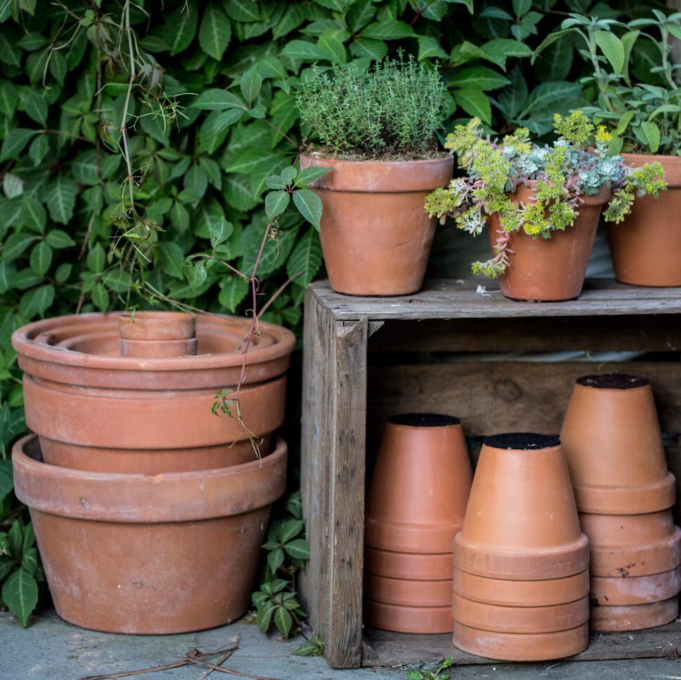 close up of stacks of terracotta flower pots on a stone floor and wooden box.