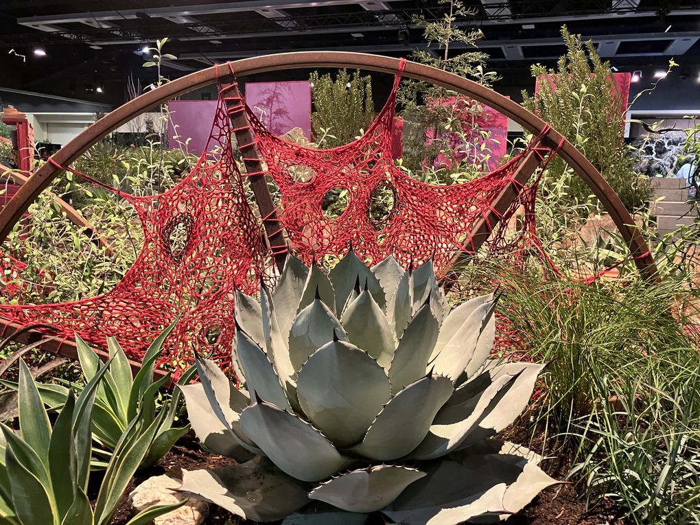 A salvaged metal wheel finished with a fiery crocheted textile piece furnished an artful screen in the Zone 9 display designed by Relish Gardens for the 2025 Northwest Flower and Garden Festival. (Courtesy Relish Gardens)