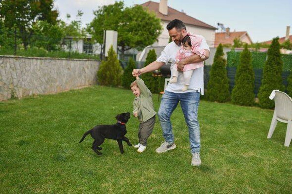 Cheerful Father Playing With Children in Yard