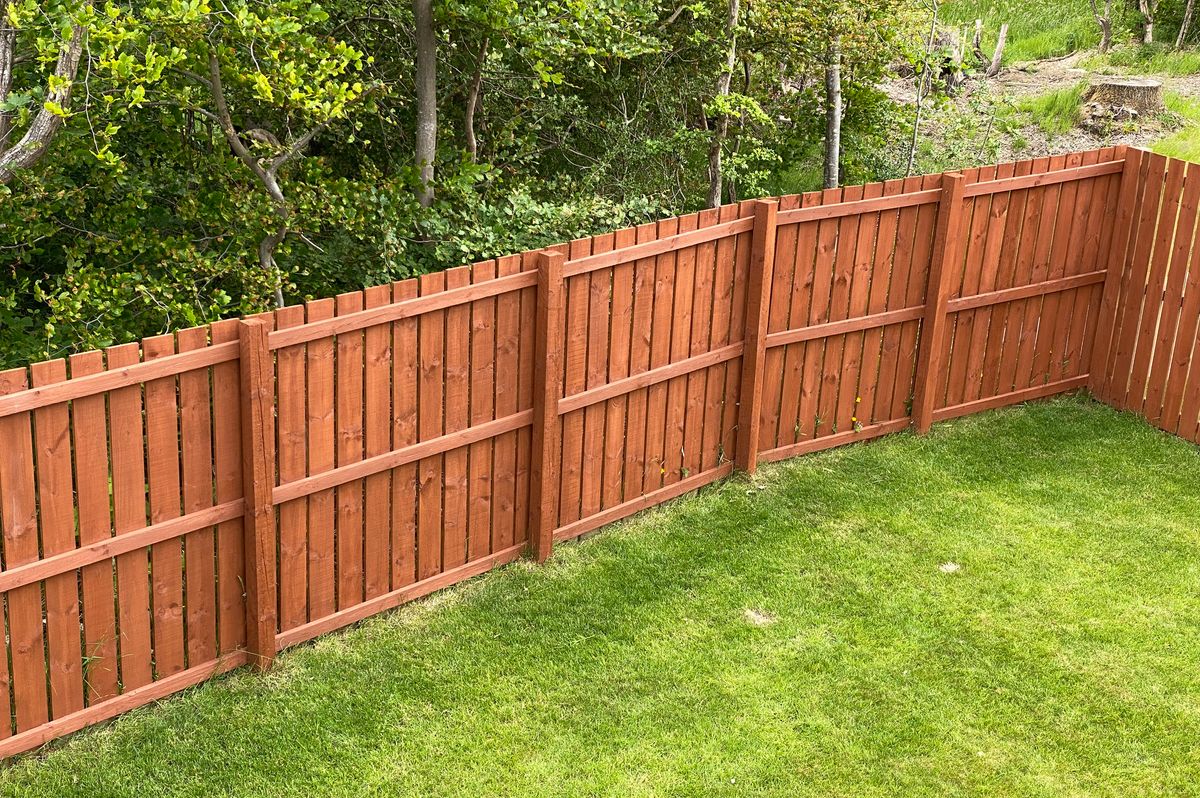 Wooden garden fence coated with medium oak colour paint UK