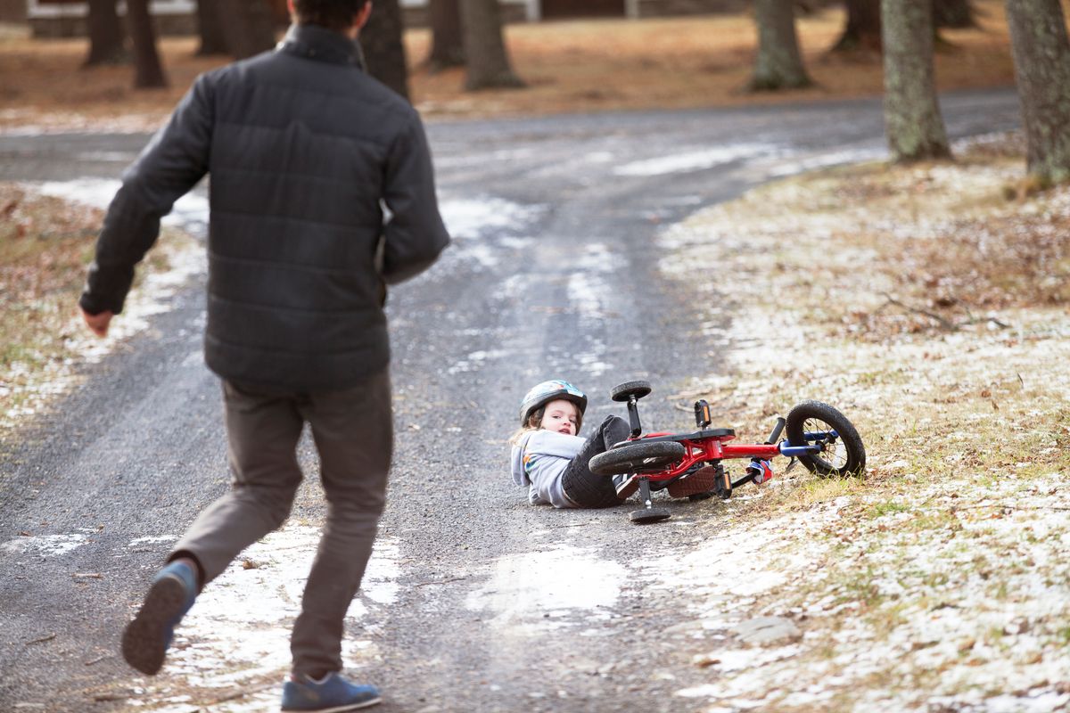 A young boy who has fell over on the ice with his bike.