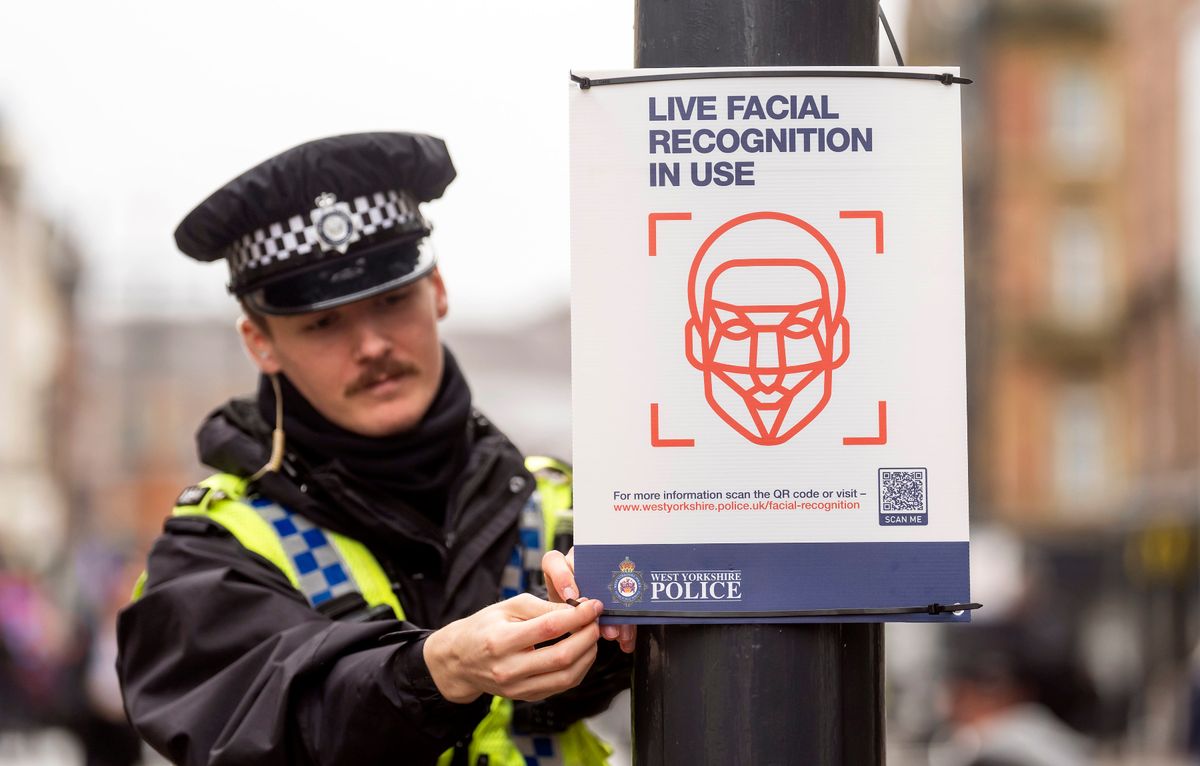 A police officer puts up a 'Live facial recognition in use' sign as a Live Facial Recognition (LFR) van is deployed on Briggate in Leeds