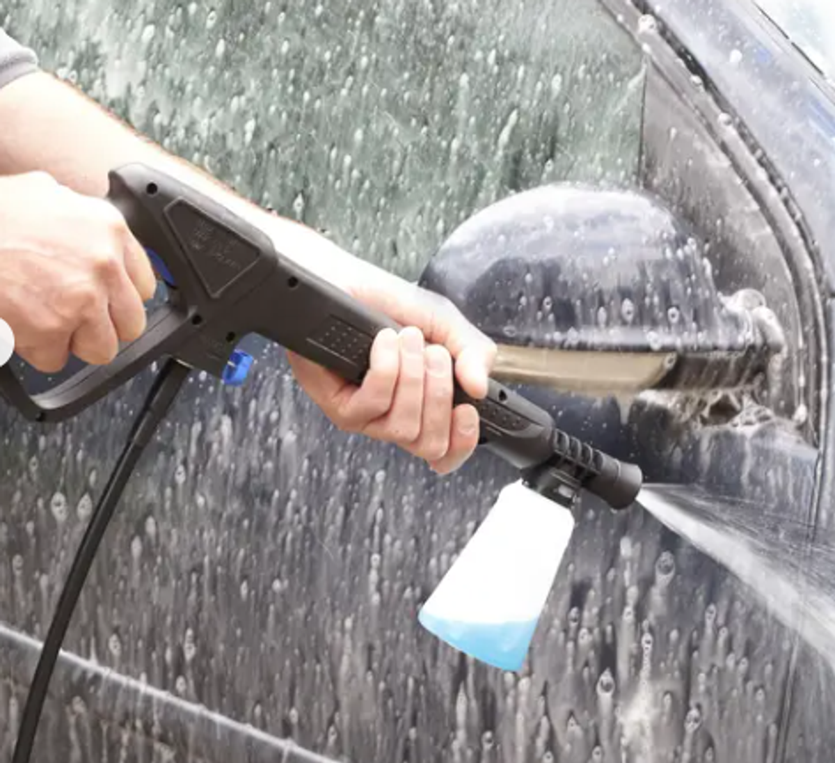 Man using high pressure washer on car