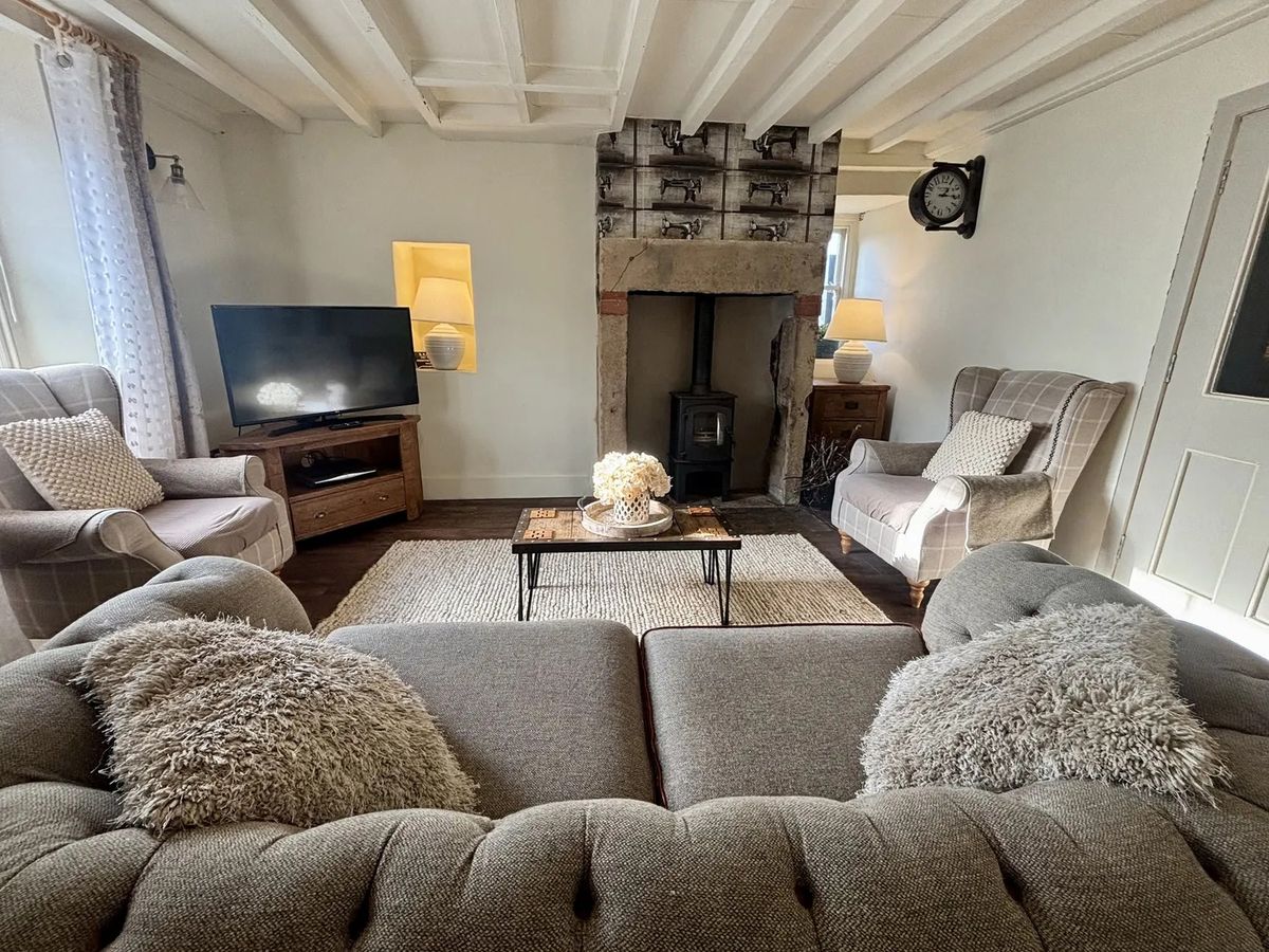 The living room area in Coupling Cottage with a sofa, two arm chairs and a TV