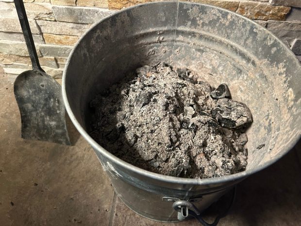 A bucket of ash appears by a fireplace at a home.