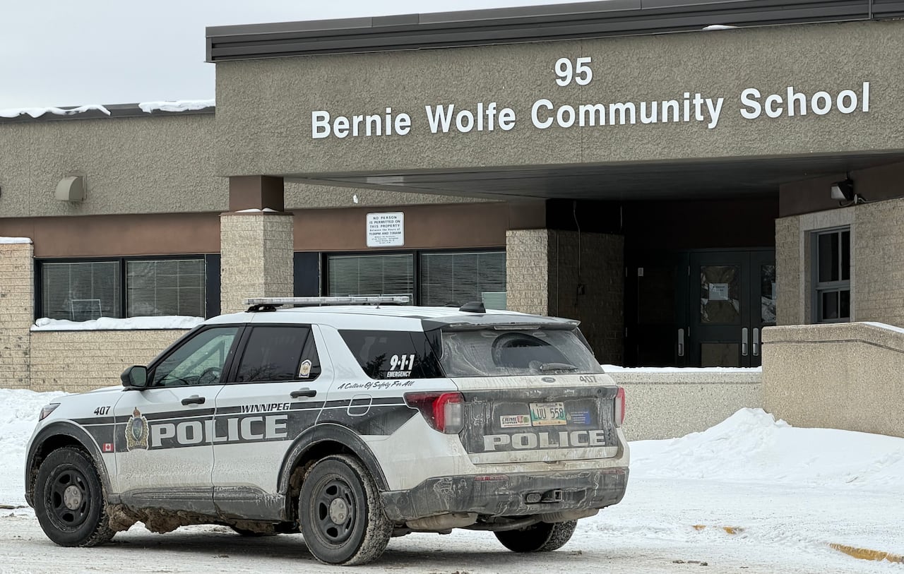A Winnipeg police vehicle is parked outside a school building with a sign that says "Bernie Wolfe Community School."