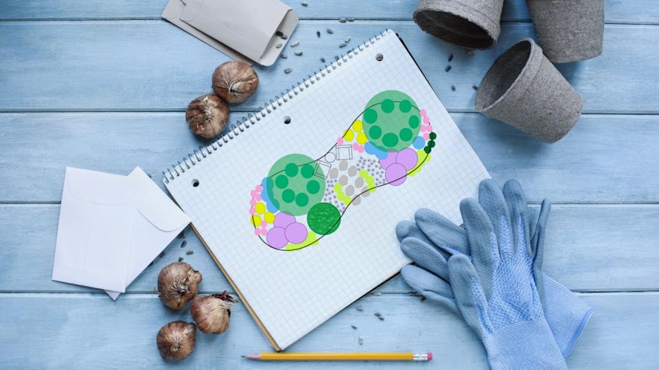 Gardening journal grid notebook with flower bed plan surrounded by garden gloves, pencil, seeds, flower bulbs, envelopes and peat pots on a rustic wooden table. Table top view.