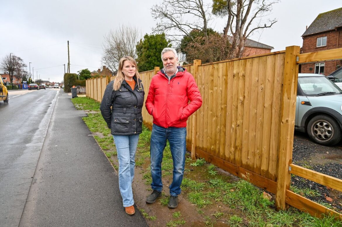 Ian and Bethany Buswell pictured in front of their new fence - which they have been ordered to take down - at their home in Hallow in Worcester.
