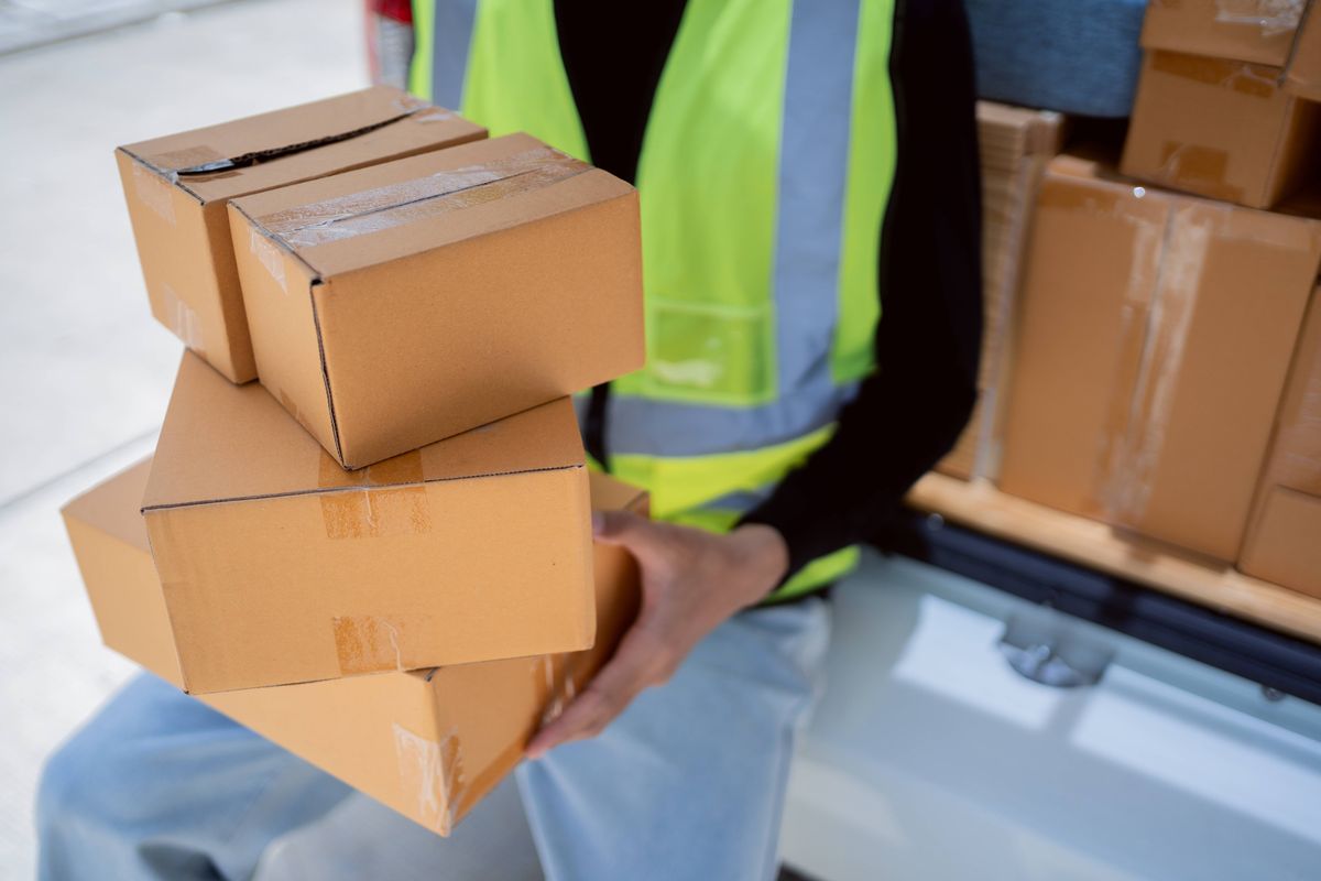 Parcel delivery man of a package through a service and customer hand accepting a delivery of boxes from delivery man.