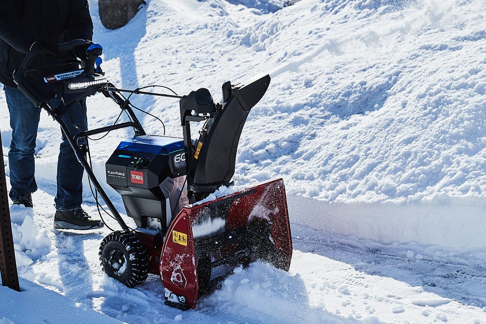 A person using a snowblower to clear snow from a pathway.