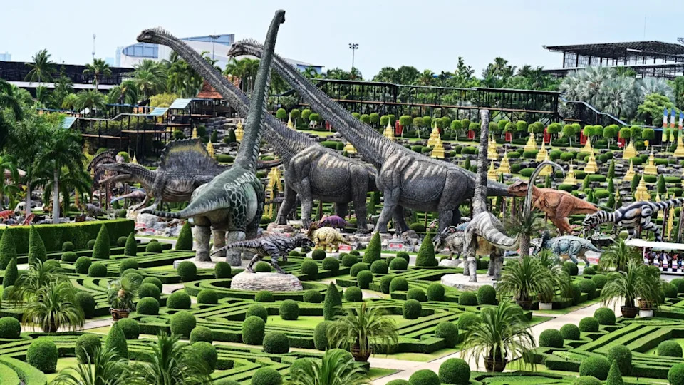 Pattaya, Chon Buri, Thailand, April 10, 2024: Panoramic view of the Nong Nooch Tropical Botanical Garden with golden stupas and models of dinosaurs.