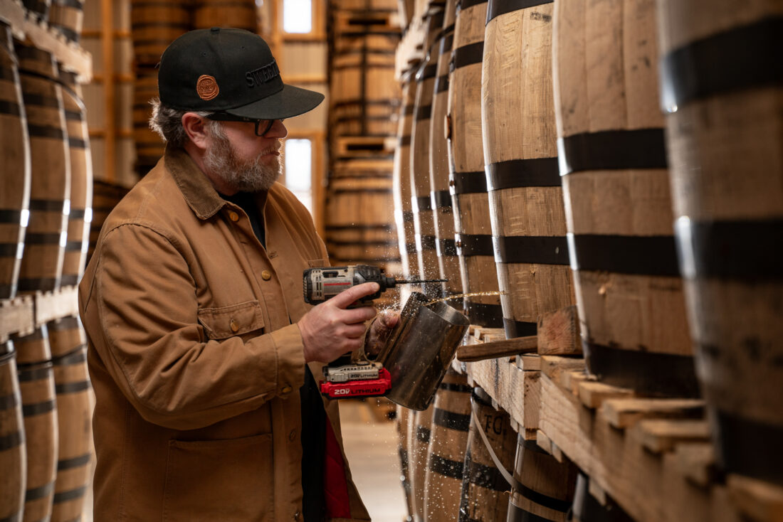 A man drills into a bourbon barrel