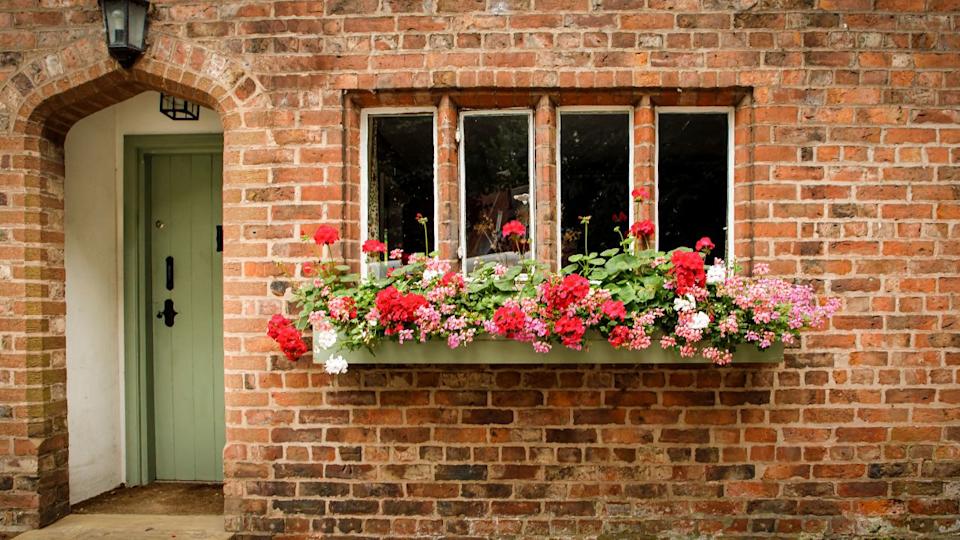 Great Budworth, Cheshire West and Chester, UK - August 17th 2024 - Front of a cottage with a window box full of flowers and a green front door in a porch