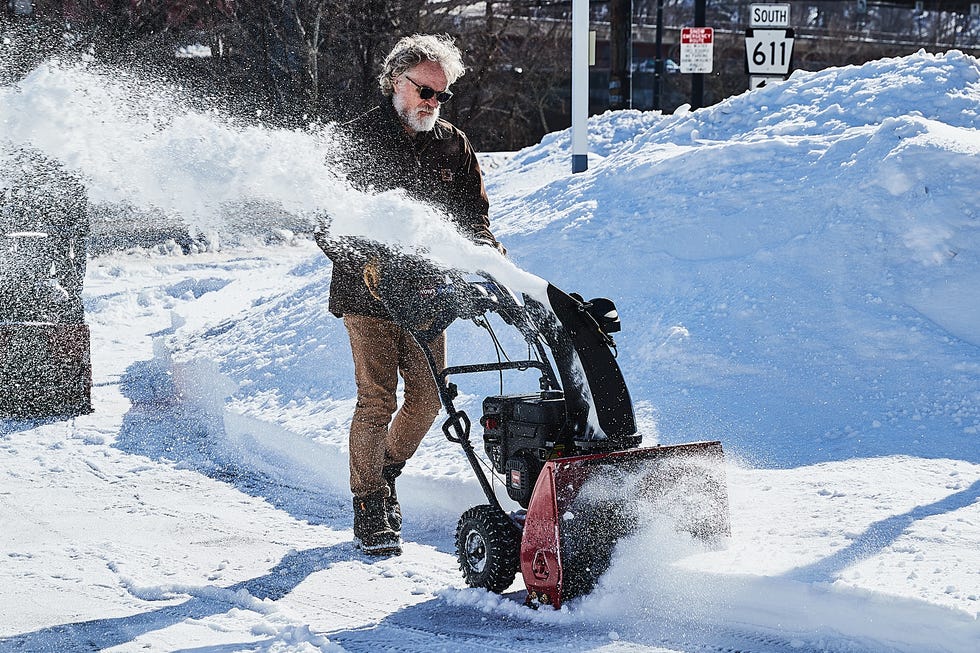 Person using a snowblower to clear snow from a path.