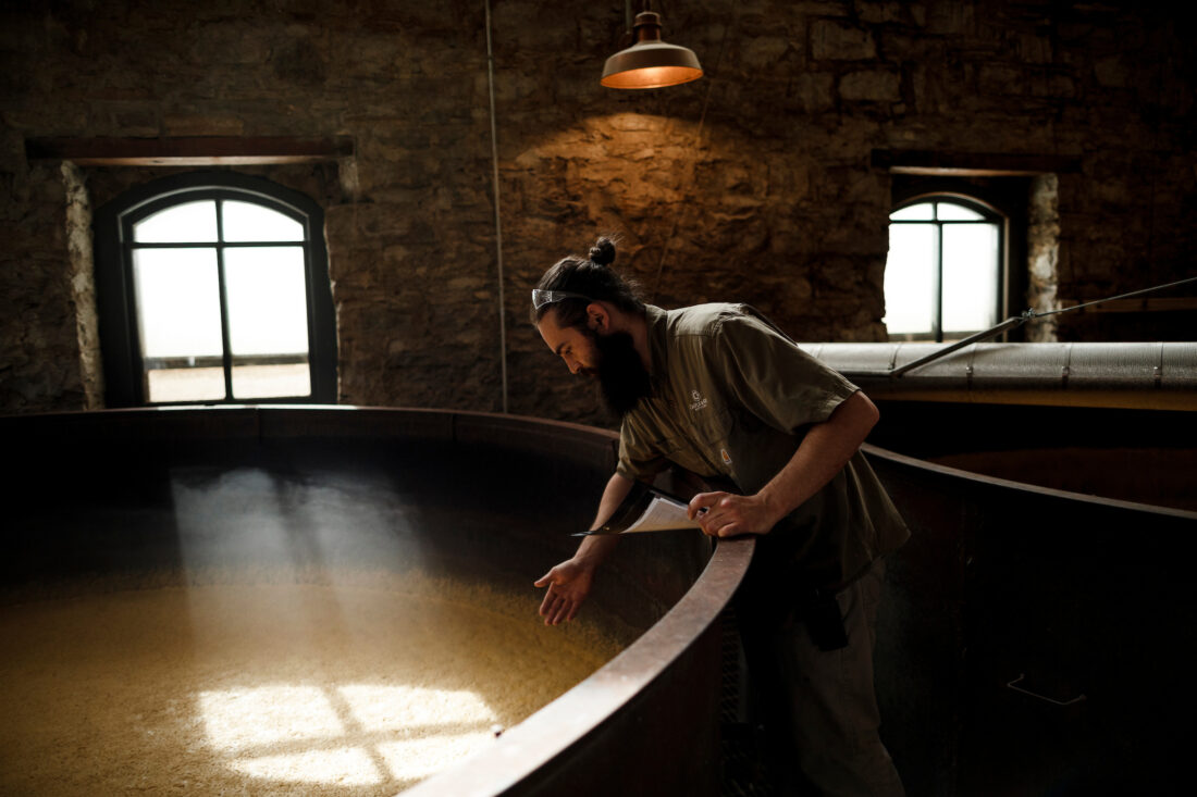 A man stands over a fermentation tank