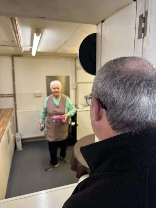 An image taken of Hazel Birkenhead, a long-time volunteer of the Llangollen Railway, just before receiving her invitation from King Charles III to Buckingham Palace's 2026 Garden Party. Taken by a colleague in the railway mess hall during the presentation.