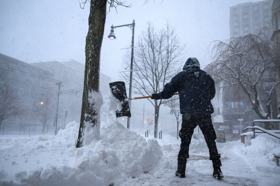 A man shovels snow off the sidewalk near Boston University during Monday's nor’easter.