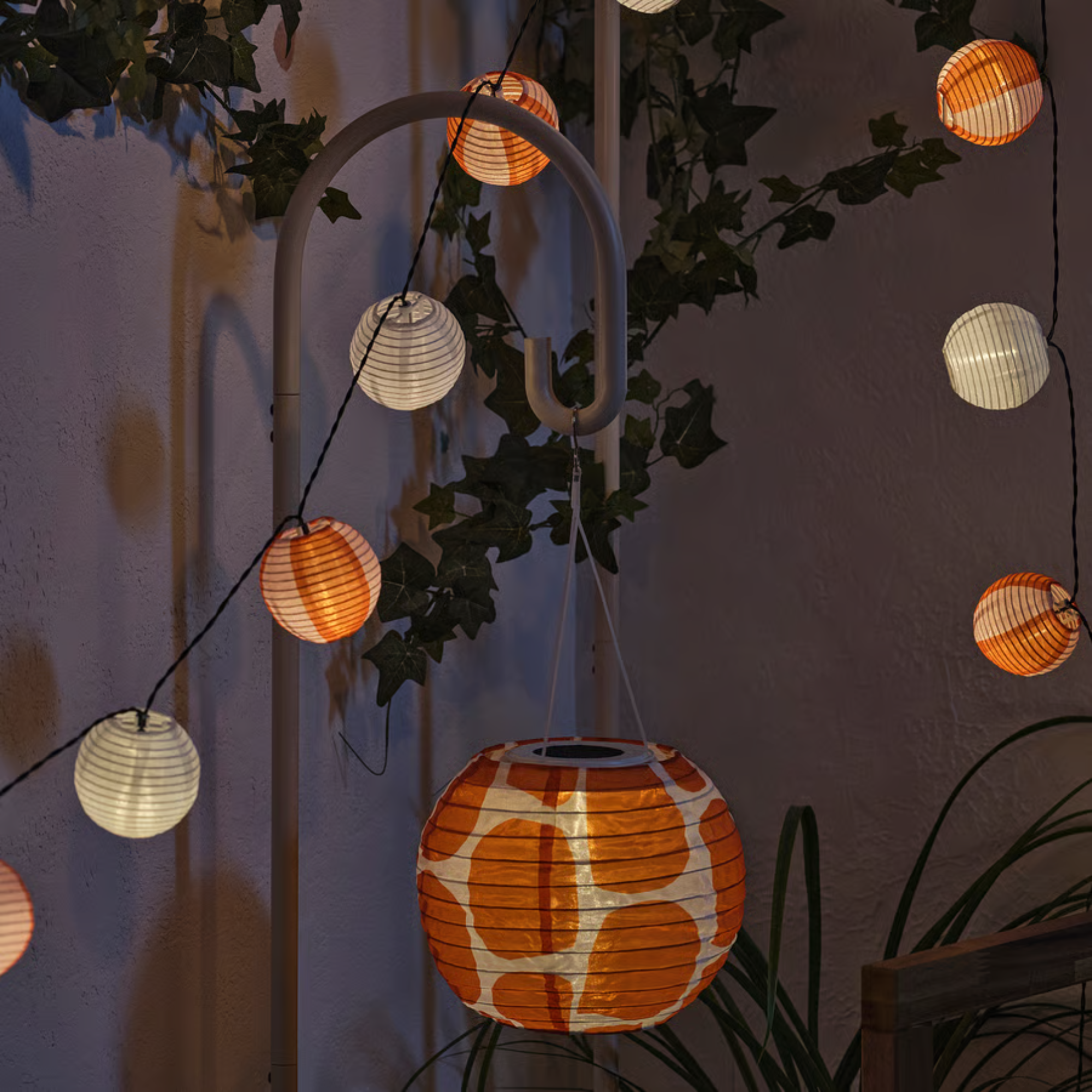 IKEA lamp stand holding a orange and white spotted lantern.