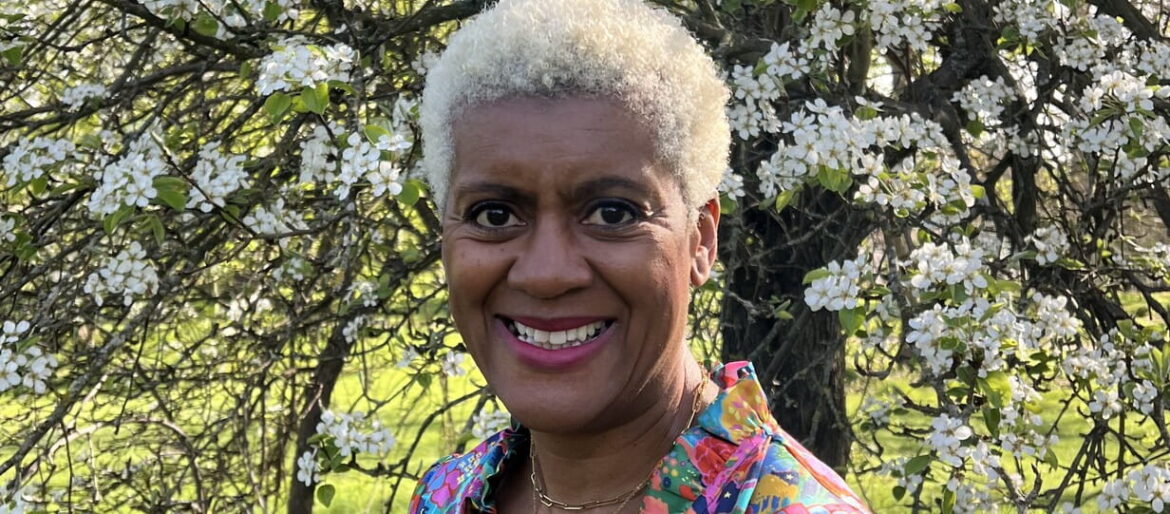 Portrait of Arit Anderson standing in front of a blossom tree