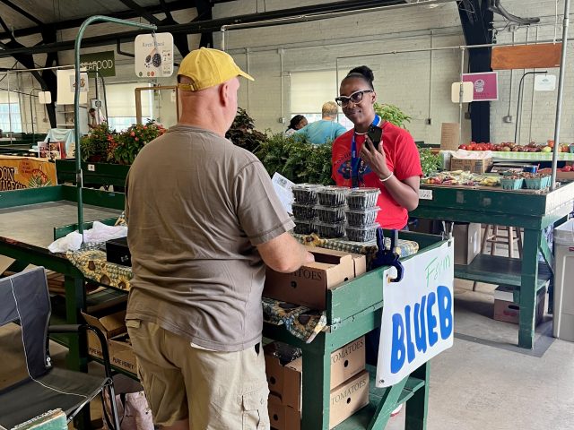 Bennett College student speaks with a local vendor at a farmers market as part of a food justice learning experience.