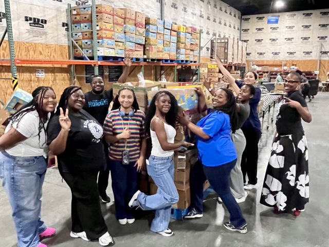 Bennett College students celebrate together while volunteering at a food distribution warehouse.