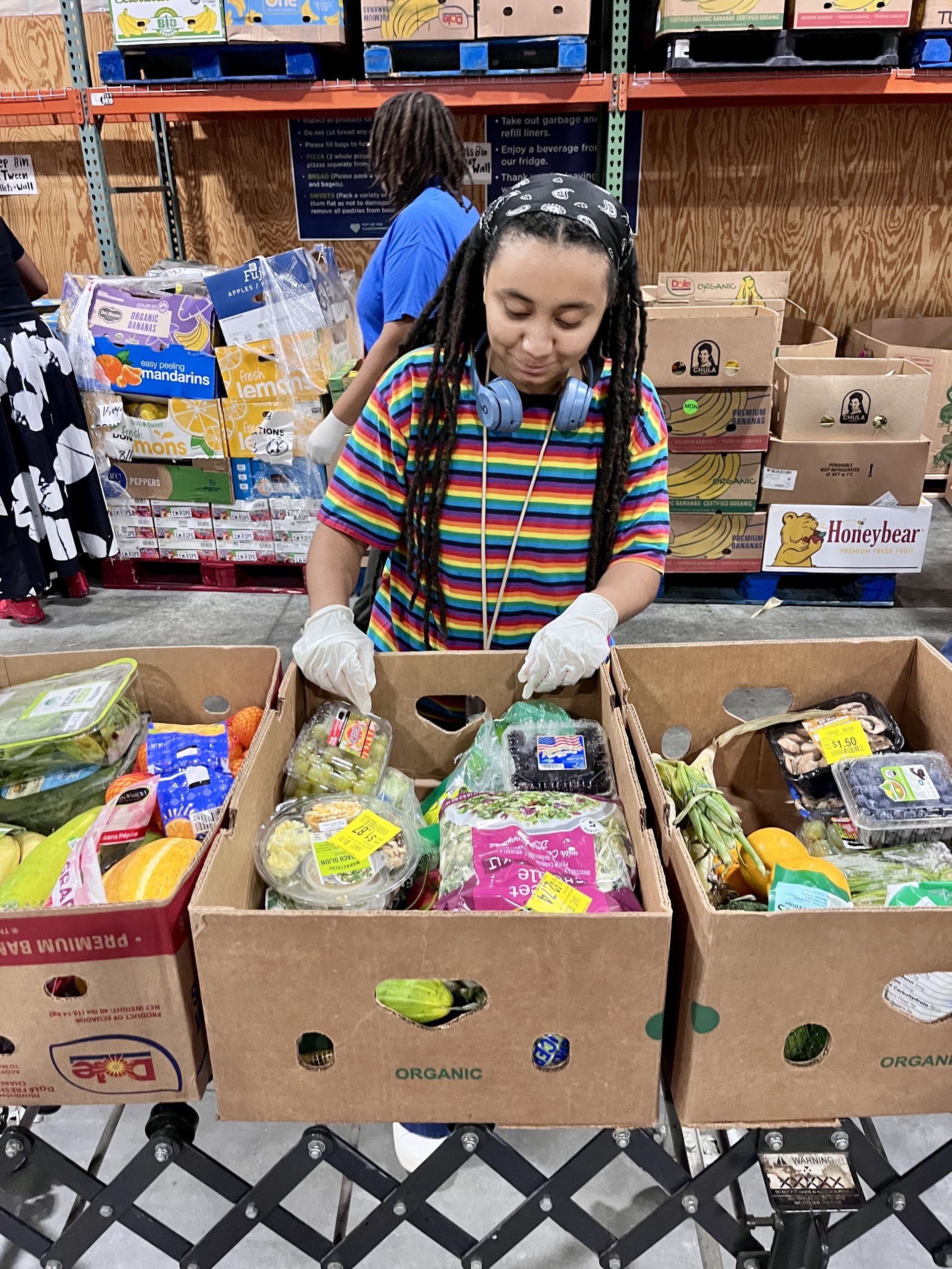 Bennett College student wearing gloves sorts fresh fruits and vegetables into boxes during a food justice service activity.