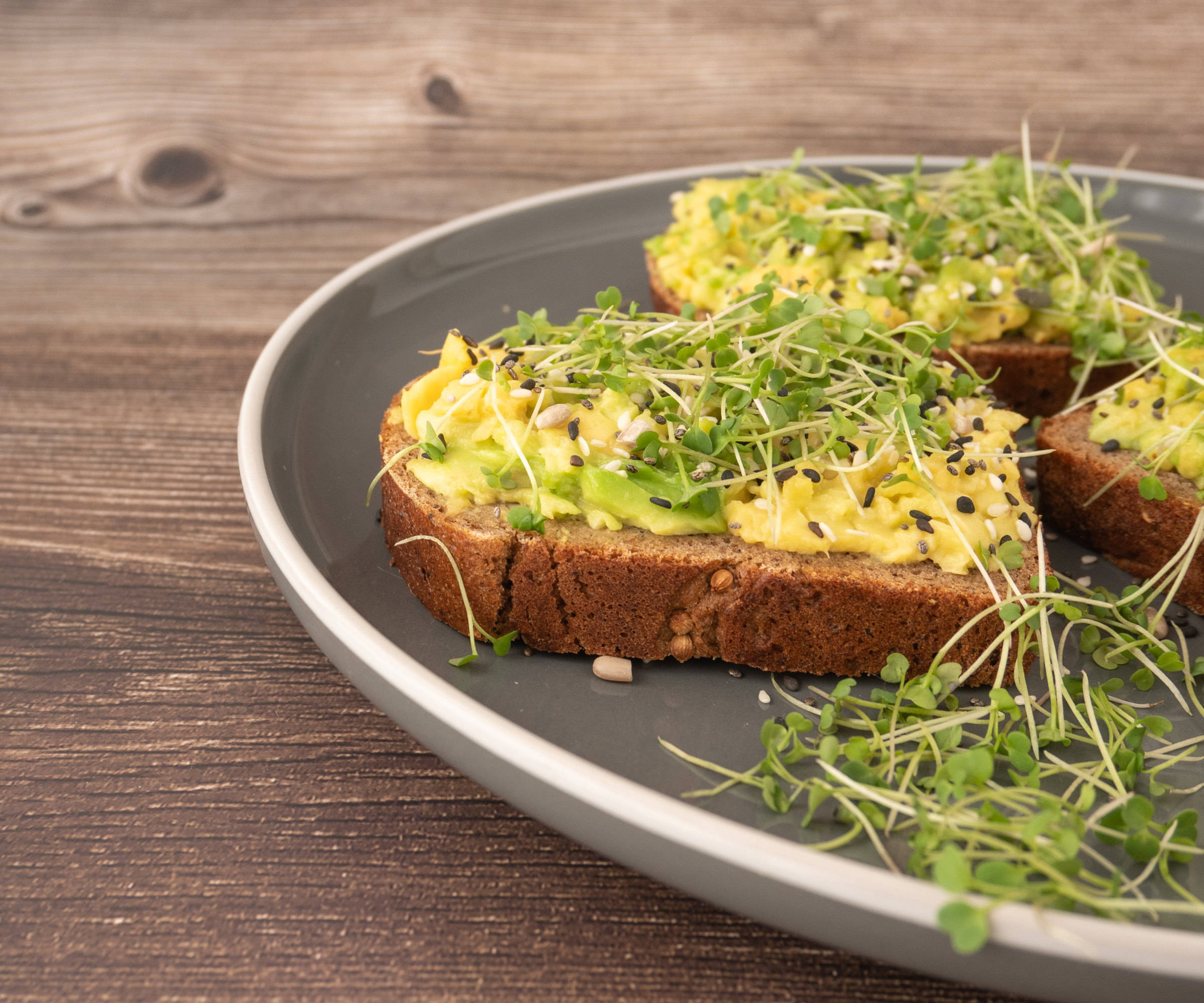 Microgreen arugula on an avocado sandwich on a gray plate