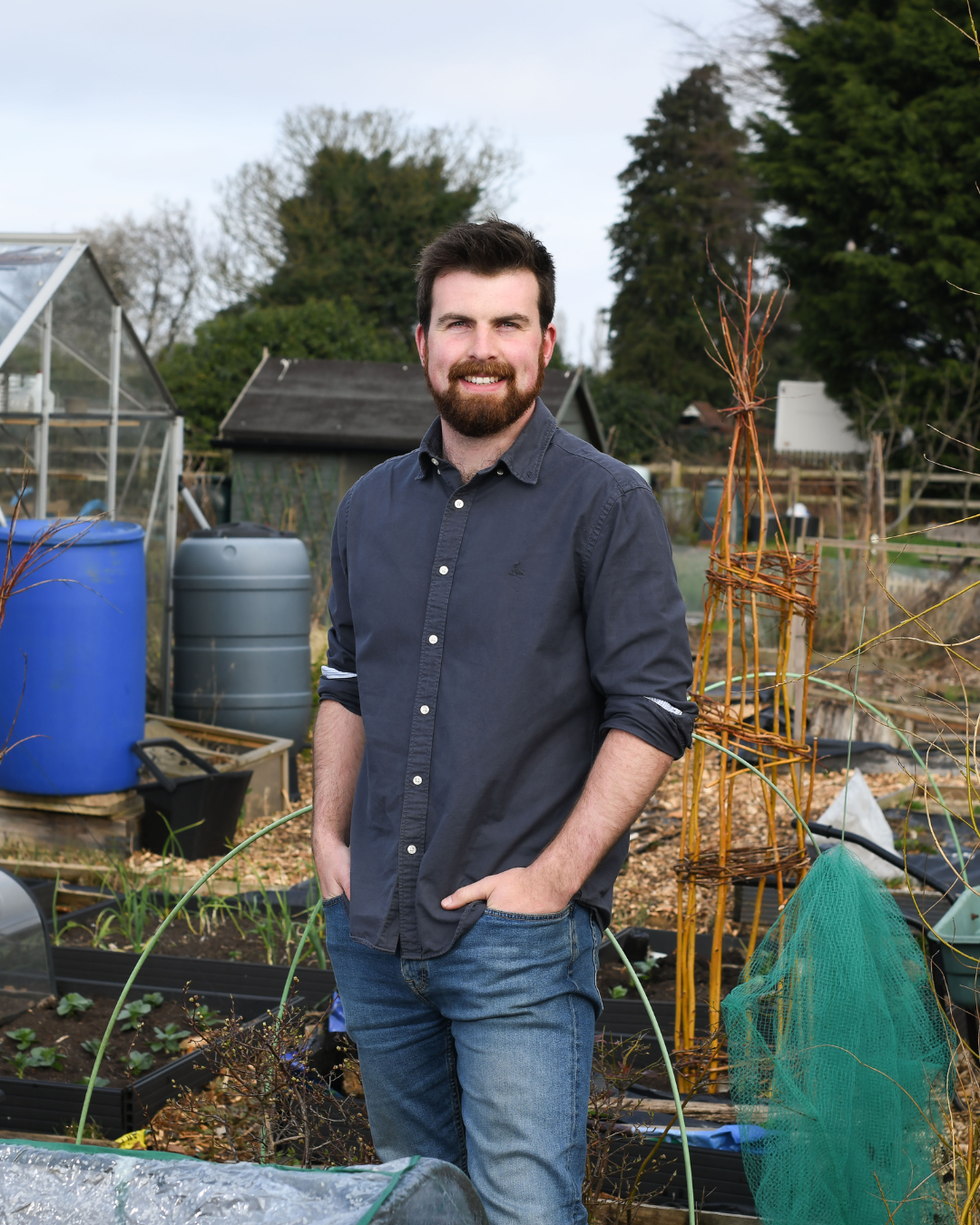 person standing in a garden area with various gardening elements