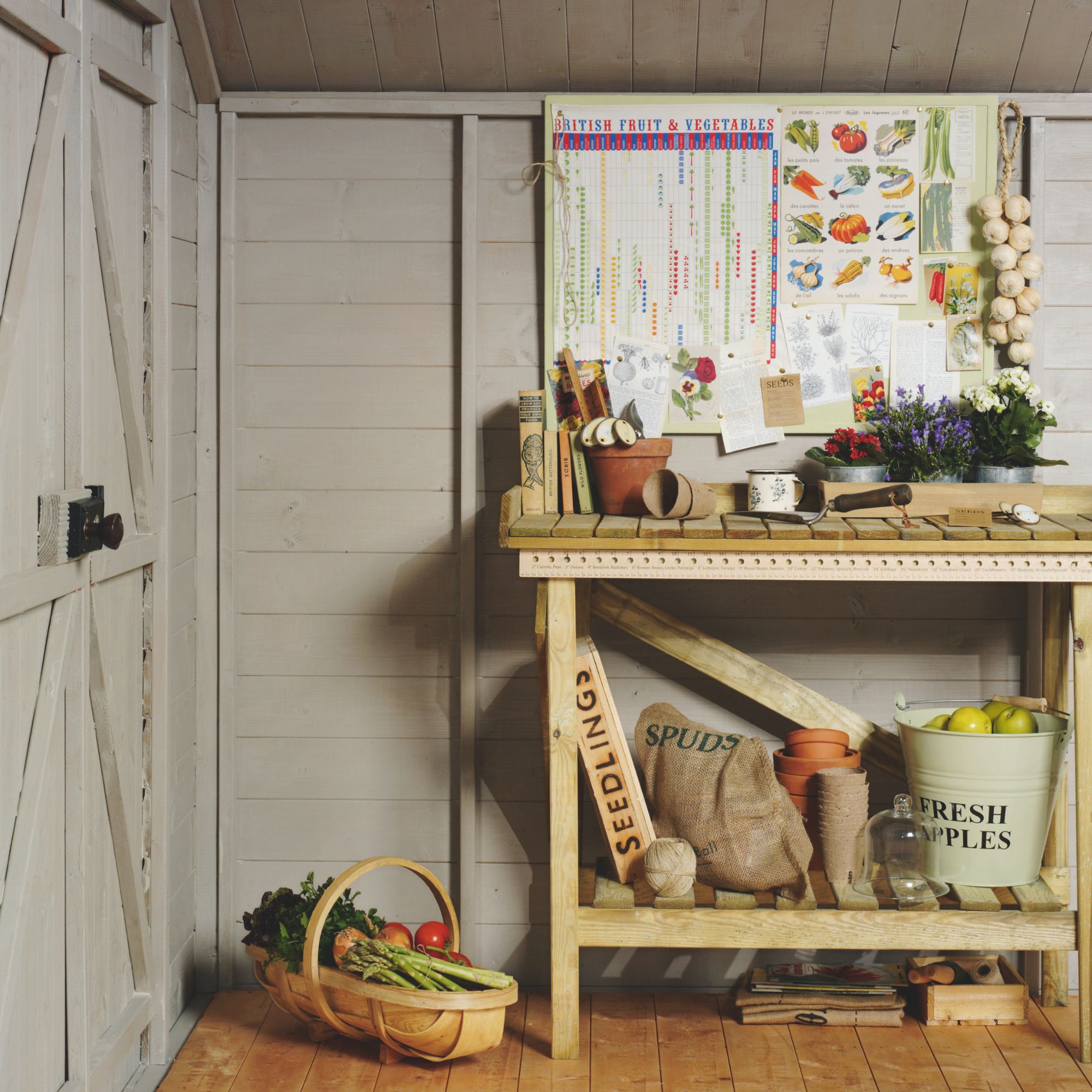 The inside of a light grey shed with a storage bench filled with gardening tools and produce