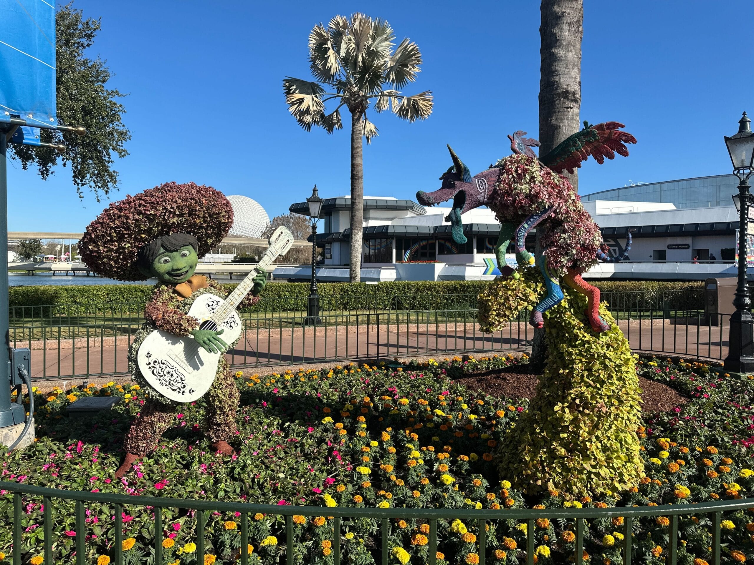 Miguel and Dante from Coco are near the Mexico Pavilion and The Odyssey. Miguel holds a guitar while Dante sticks his tongue out atop a tower of marigolds.