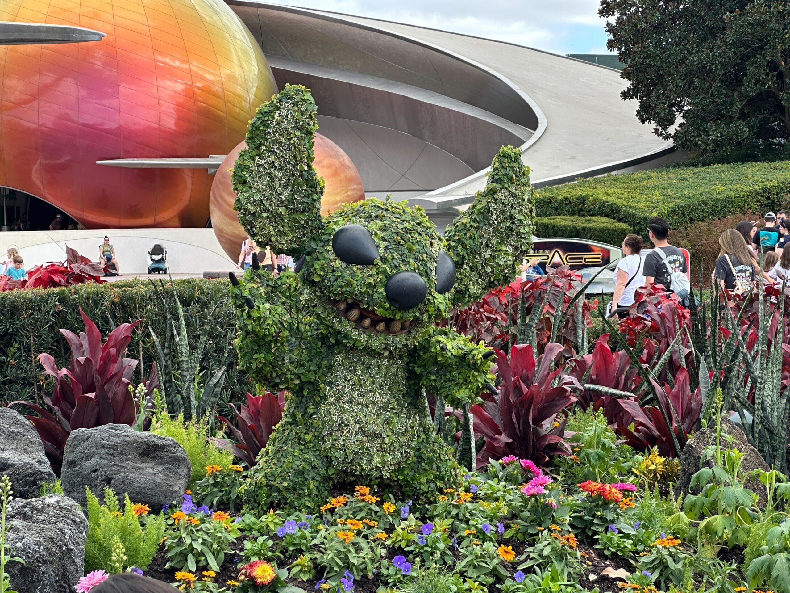 The Stitch topiary is placed inside a flower bed near Mission: SPACE.