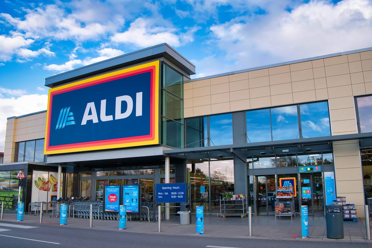 The frontage and brand logo of a branch of German discount retailer Aldi, taken in a local retail park on Wirral, UK on a sunny afternoon
