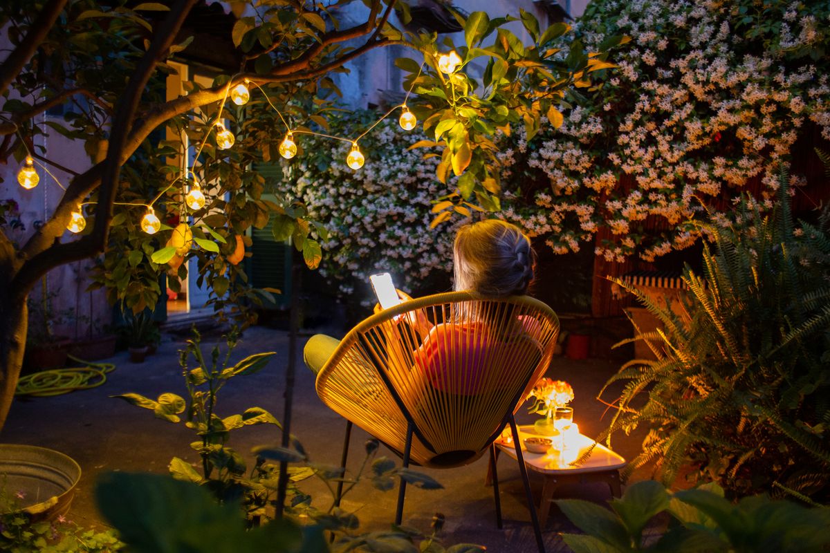 Woman relaxing in garden chair after dark
