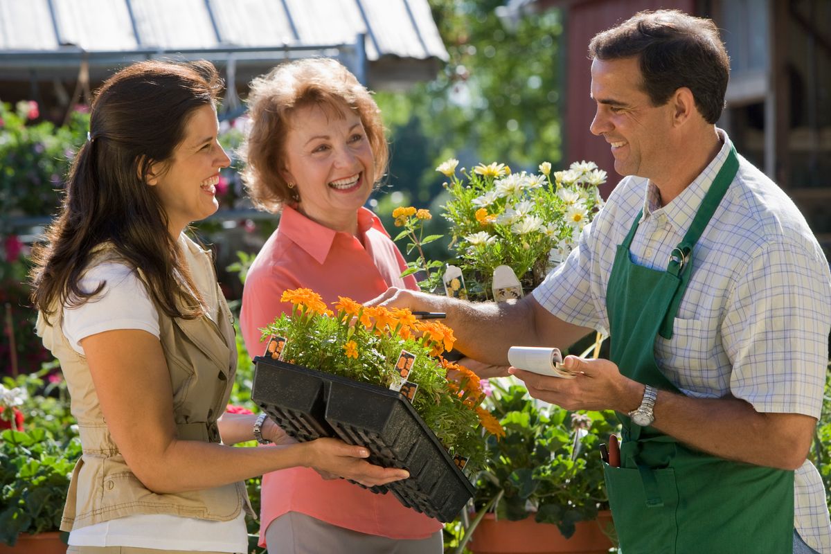 Two women smile as they chat to man working in garden centre