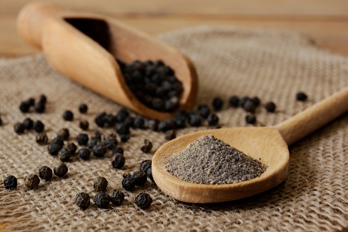 Ground Black Pepper and Peppercorns with wooden spoon and scoop.Studio shot on June, 18, 2018